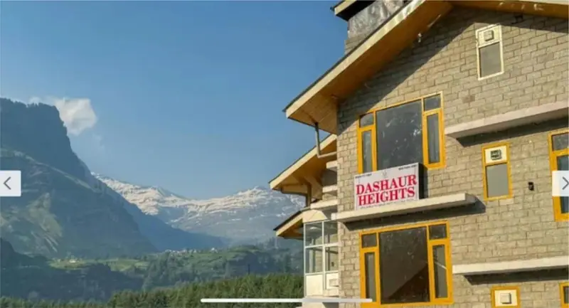 Dashaur Heights hotel building overlooking the snow-capped Himalayan valley in Burwa, Manali